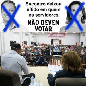 Foto dos candidatos Nando e Telma de costas e no fundo a plateia de servidores. Em cima dessa foto tem uma montagem com as fotos dos candidatos Rogério Santos e Rosana Valle com um Xis na cara de cada um e escrito "Encontro deixou nítido em quem os servidores NÃO DEVEM VOTAR"