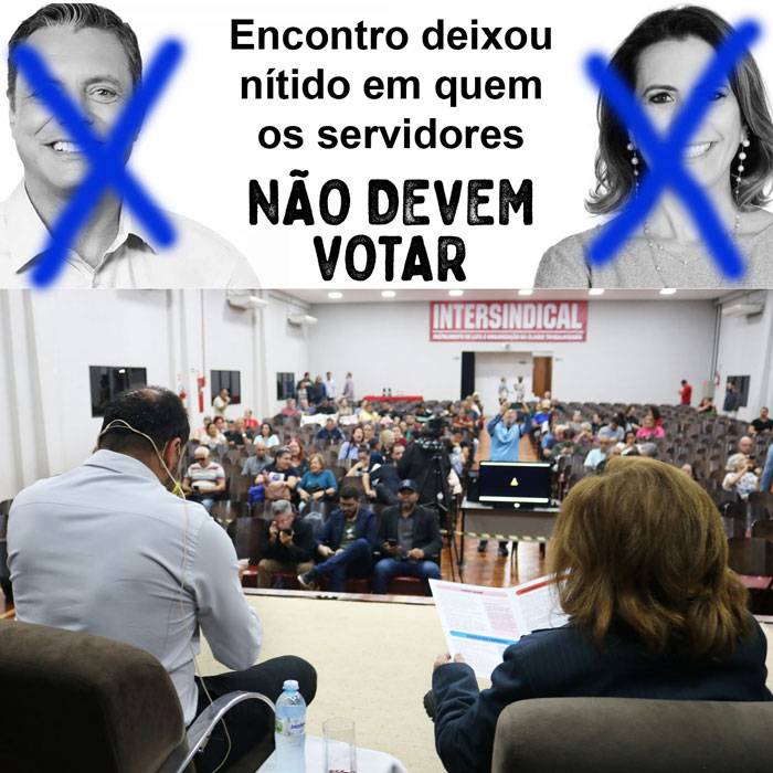 Foto dos candidatos Nando e Telma de costas e no fundo a plateia de servidores. Em cima dessa foto tem uma montagem com as fotos dos candidatos Rogério Santos e Rosana Valle com um Xis na cara de cada um e escrito "Encontro deixou nítido em quem os servidores NÃO DEVEM VOTAR"