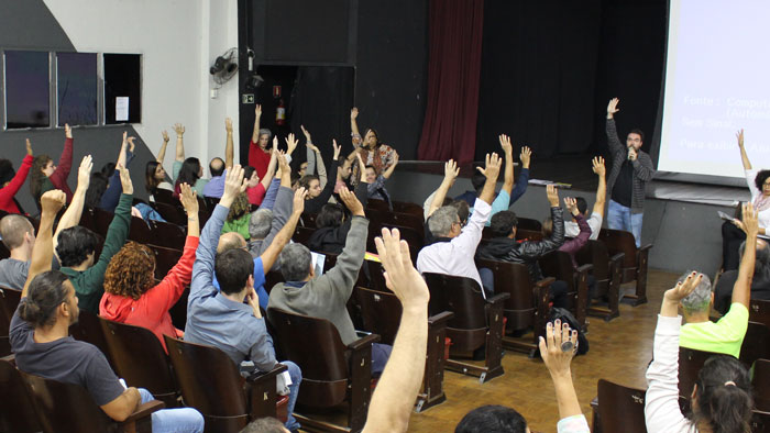 Foto da votação. Todos de braço levantado aprovando a greve.
